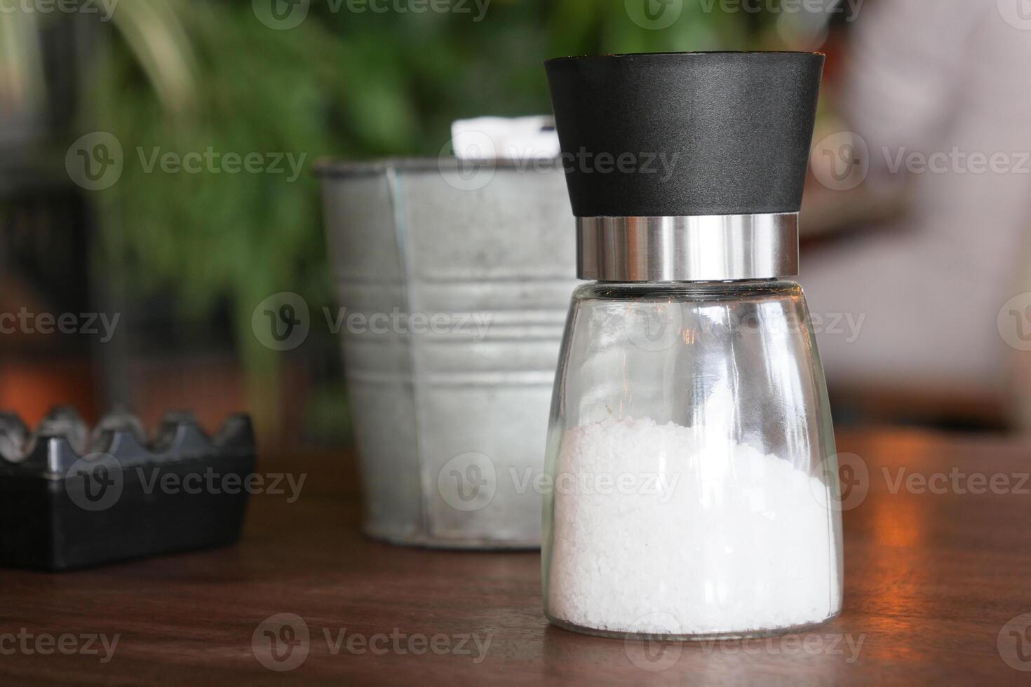 A stylish glass salt shaker beautifully displayed on a rustic wooden table photo