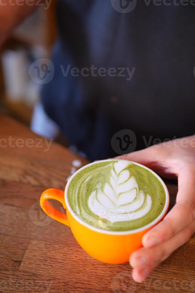 Artistic Green Latte presented in a strikingly vibrant orange cup photo