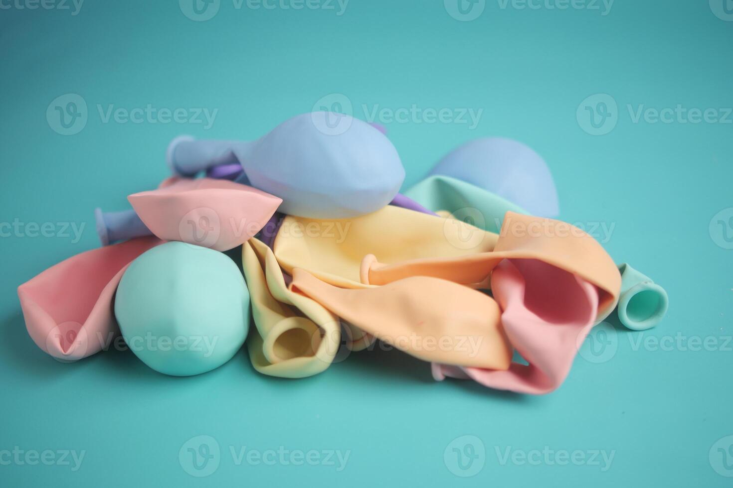 A Variety of Colorful Balloons Piled Together on a Vibrant Teal Background photo