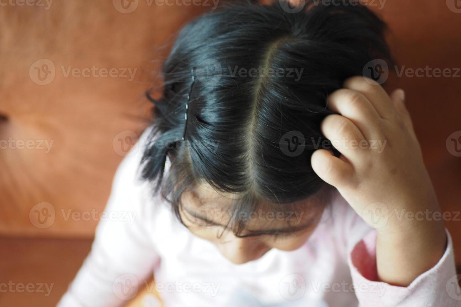 A Child with Curly Hair Engaged in Thought While Sitting on a Couch photo
