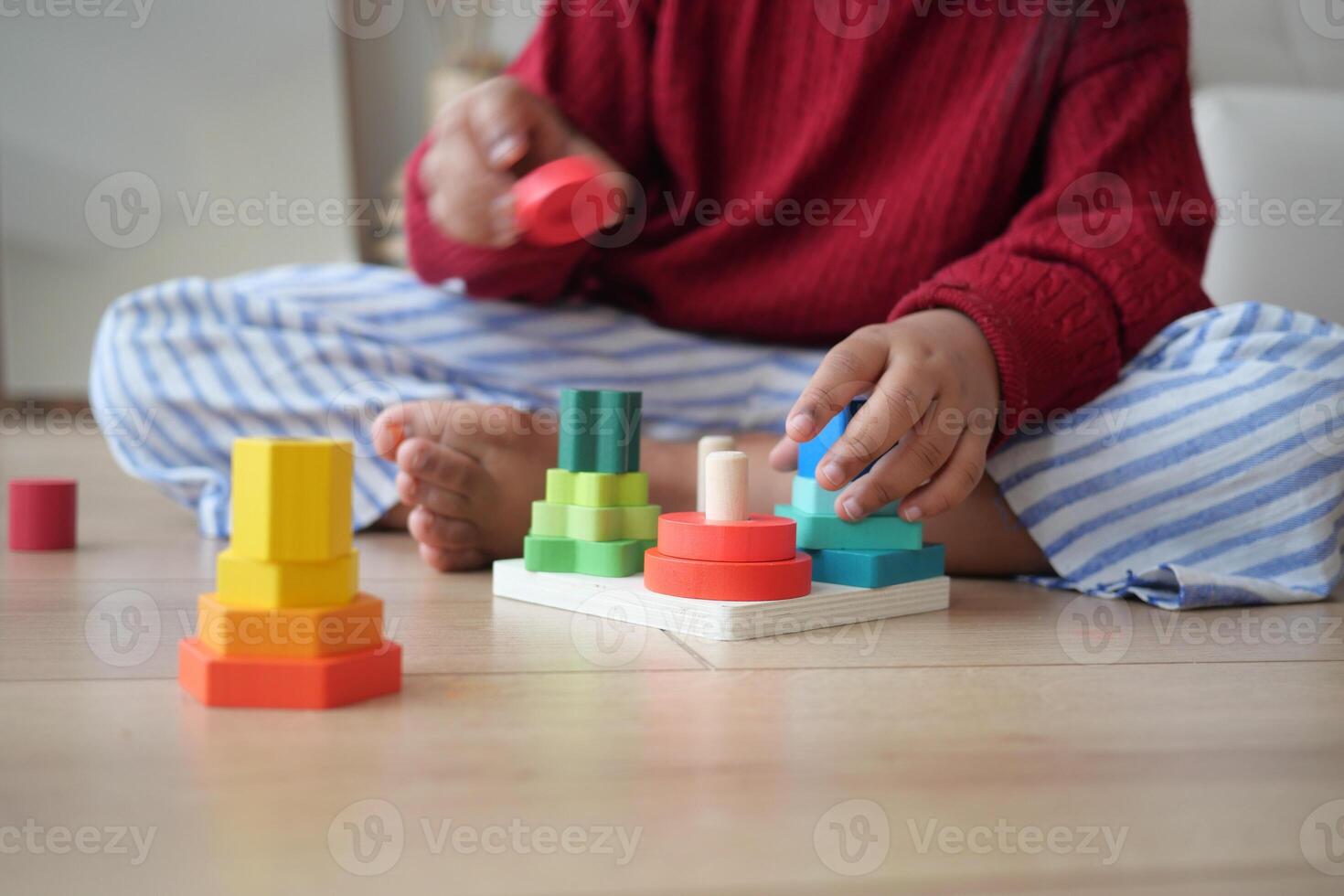 A Child Enjoys Playing with Vibrant and Colorful Stacking Toys on a Wooden Floor photo