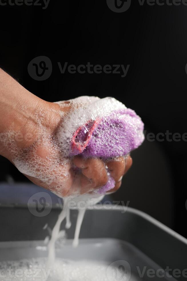 Washing a Colorful Sponge with Soap Suds in One Hand, Engaging in Cleaning photo