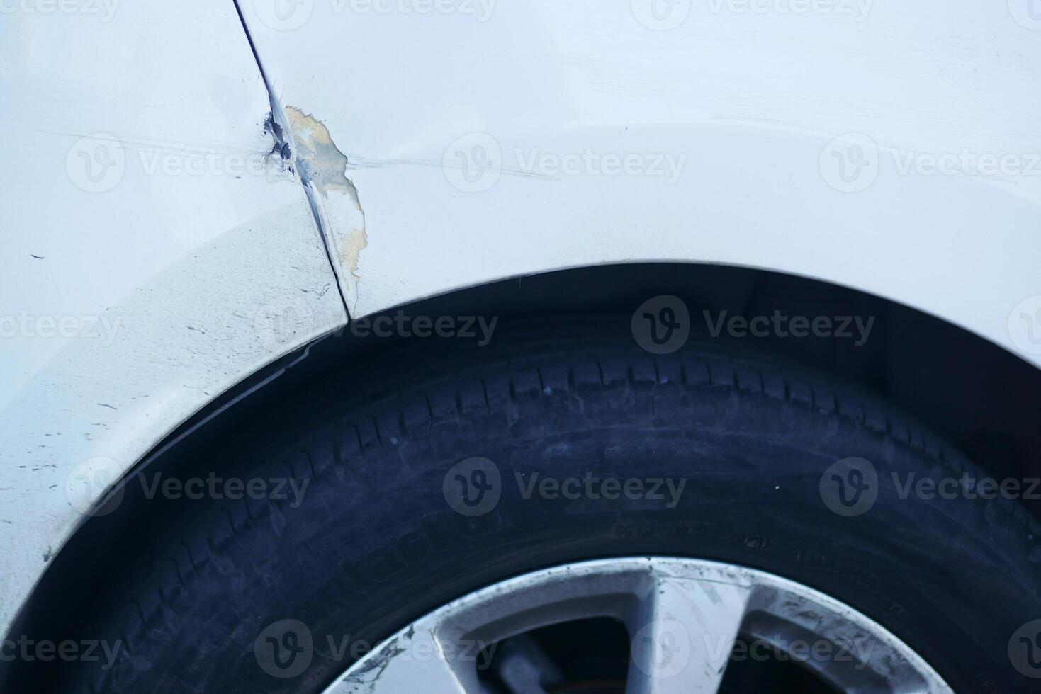 A detailed closeup image showcasing the damaged fender and tire of a car photo
