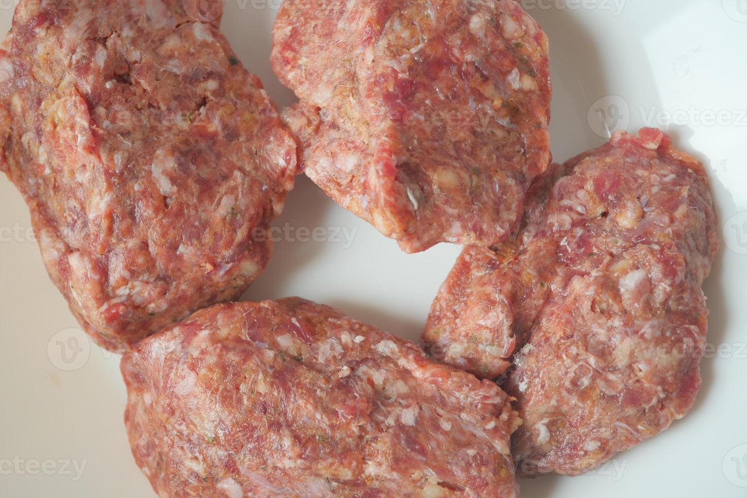 Fresh Ground Meat Portions Displayed on a White Plate Ready for Cooking photo