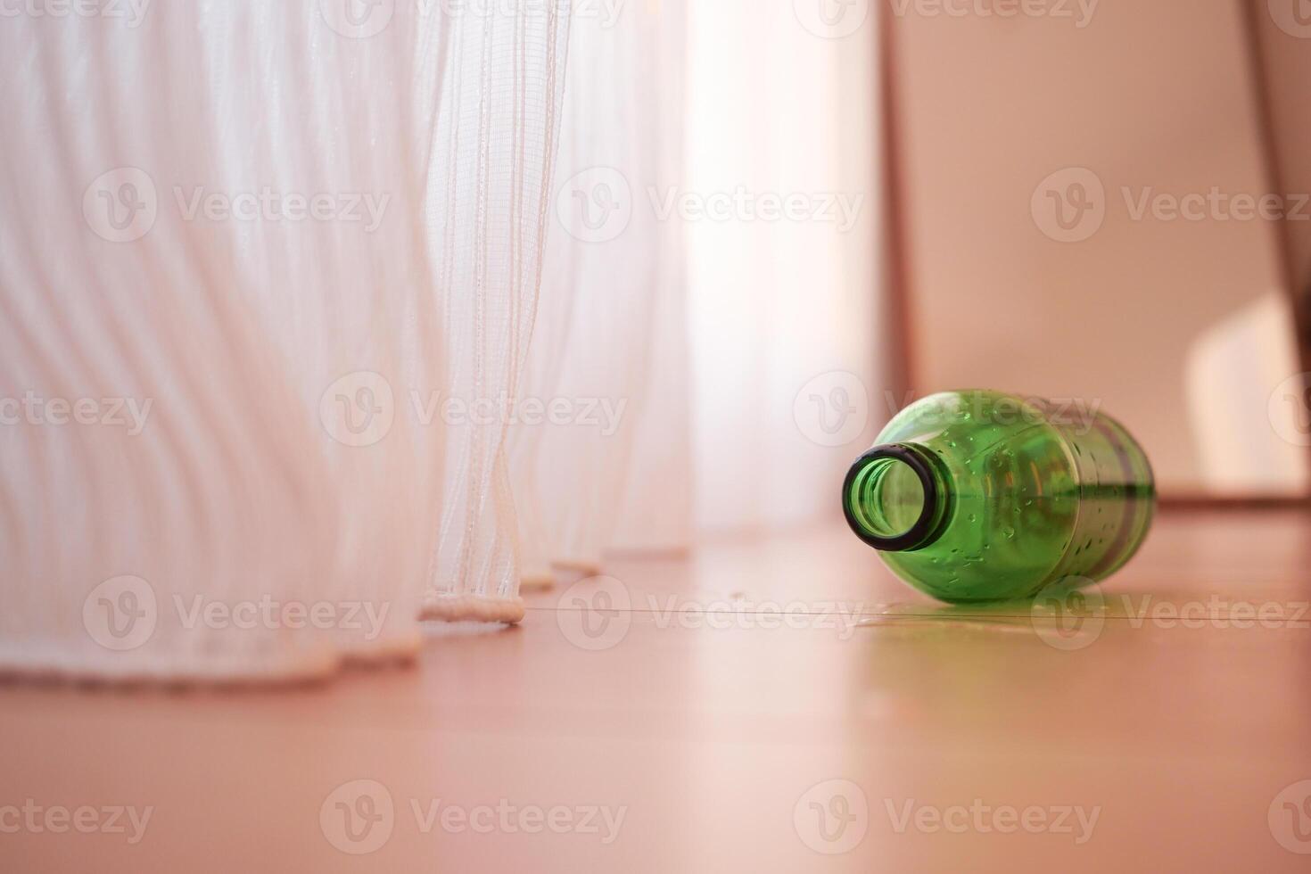 A Green Plastic Bottle is lying on the Floor illuminated by Natural Light photo