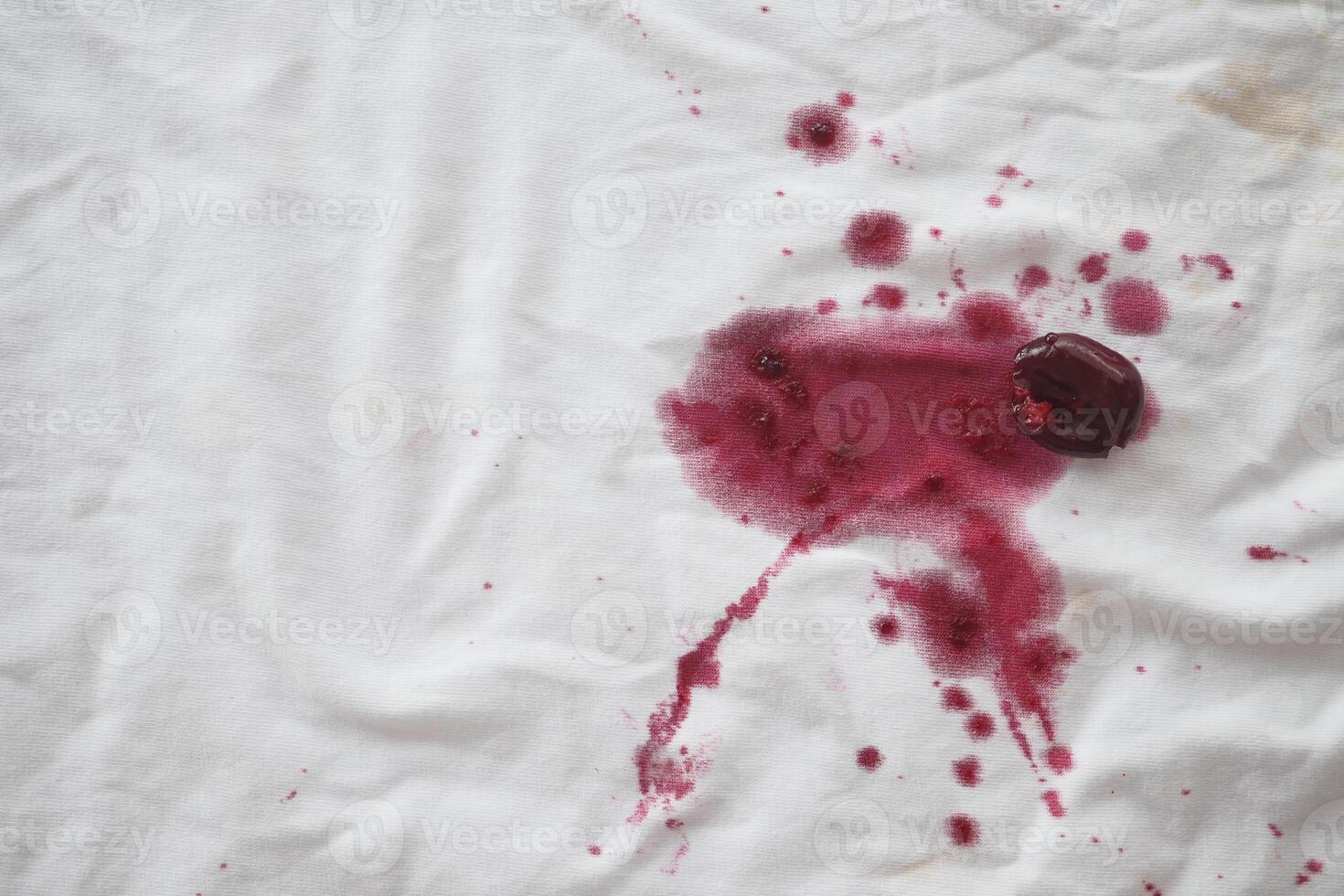 There is a spill of red wine on the white fabric, creating a noticeable stain photo