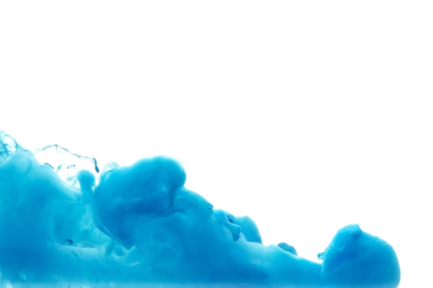 Blue ink dropped in to water isolated white background. Abstract color dissolving in water photo