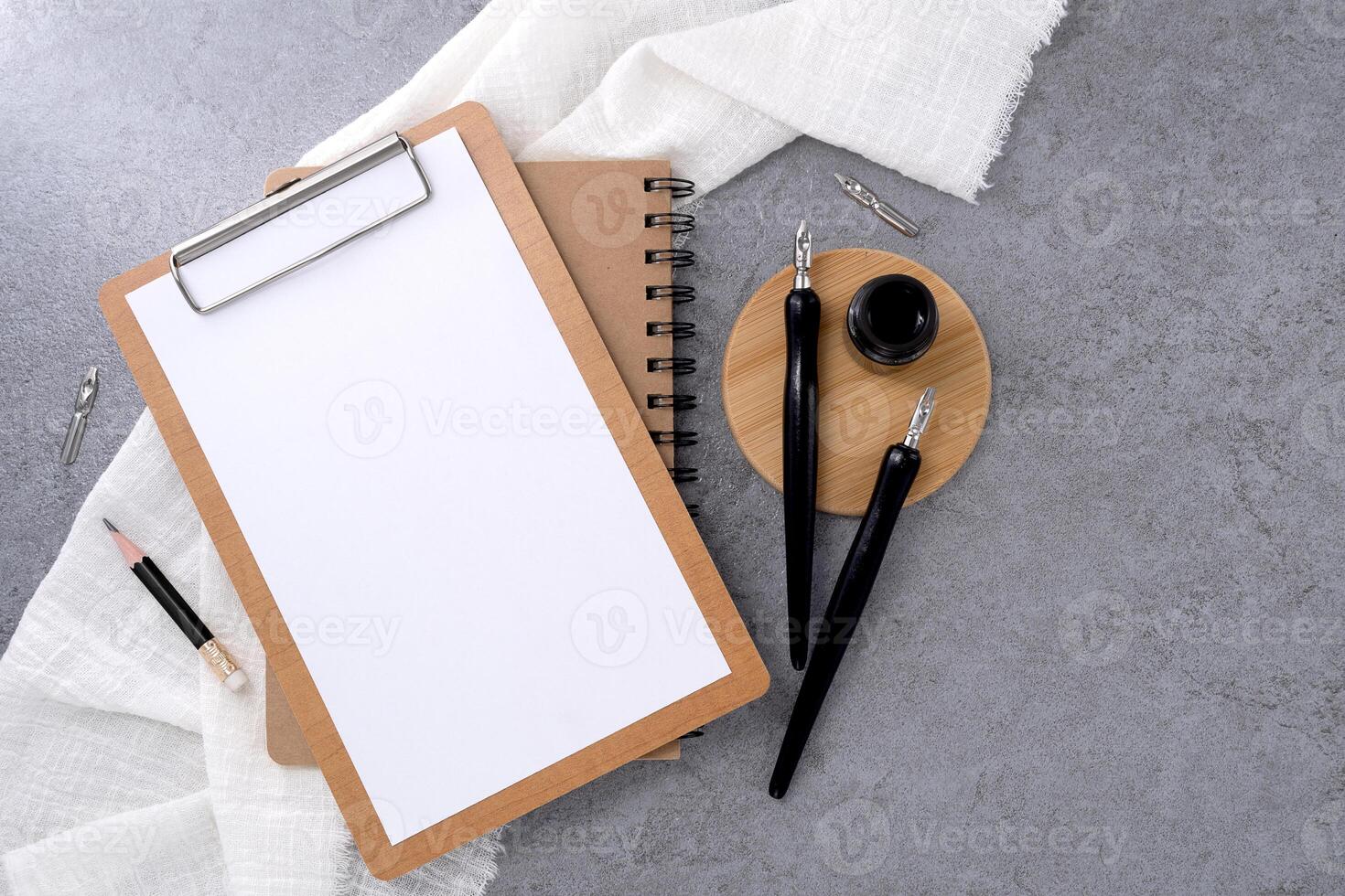 Blank clipboard and dip pen on stone texture background. Writer workplace concept. photo