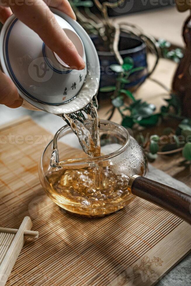 Pouring aromatic tea into a beautiful teapot surrounded by greenery, enhancing elegance photo