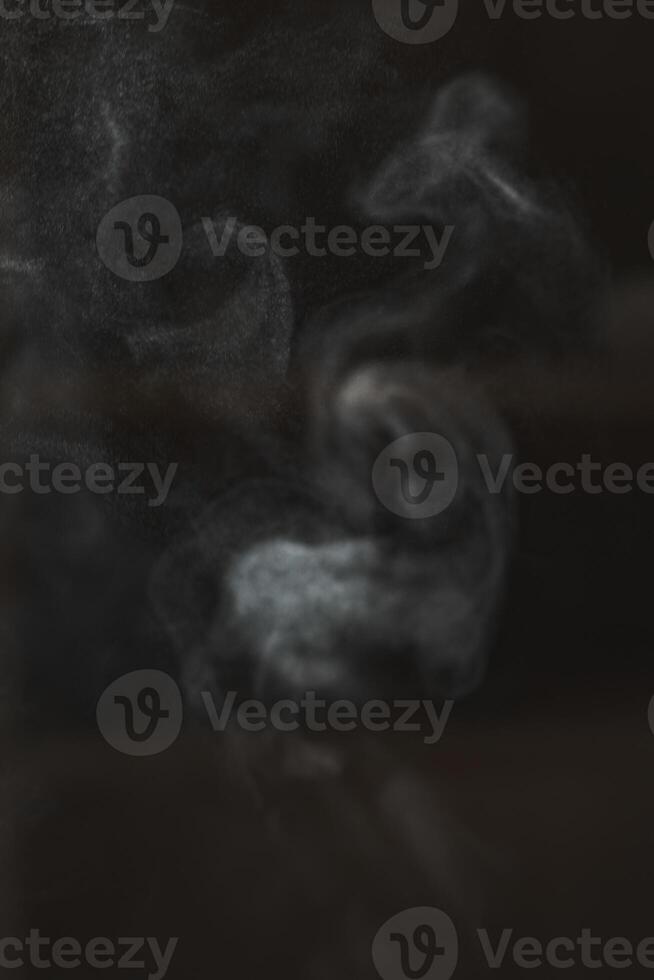 Ethereal and captivating smoke patterns emerge gracefully against a dark, rich background photo