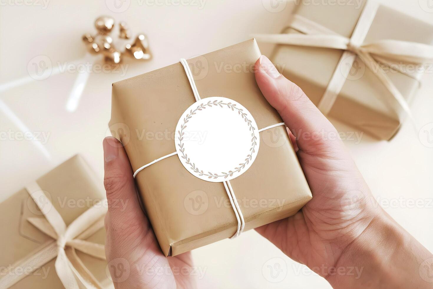 A person is holding a brown color gift box, and a blank white label sticker mockup is attached on it photo