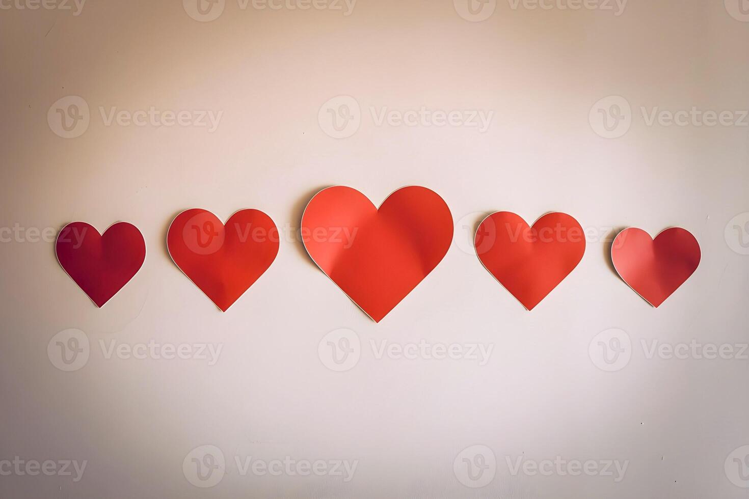 Five different sizes red heart stickers are attached on a background wall representing mockup as well photo