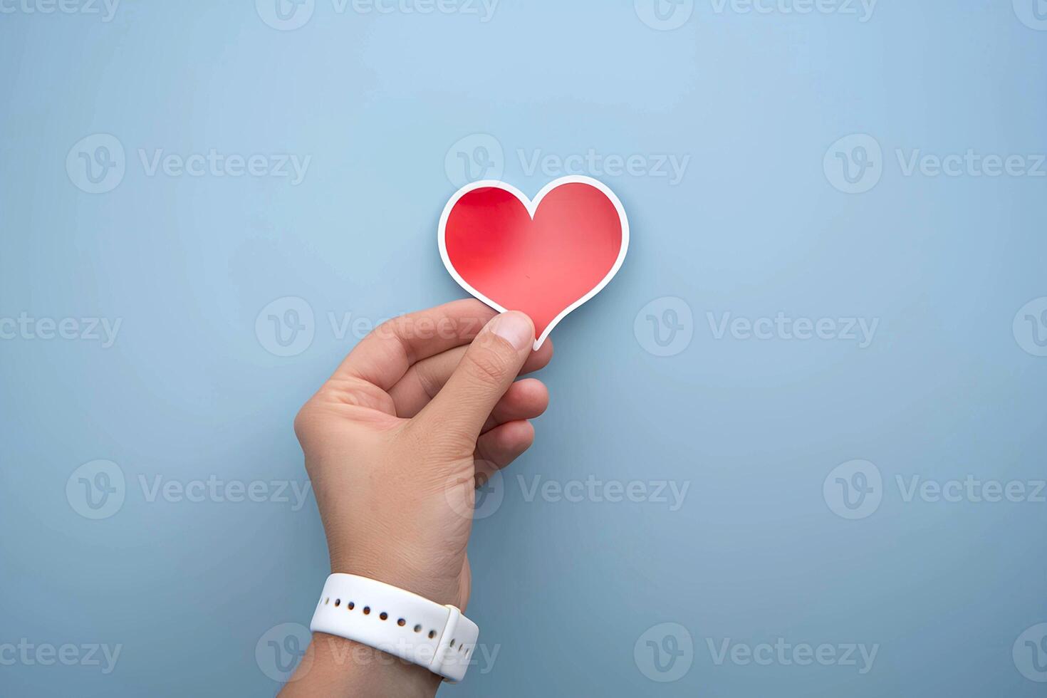 A person hand is attaching a cute red heart sticker on a blue background wall representing a mockup photo