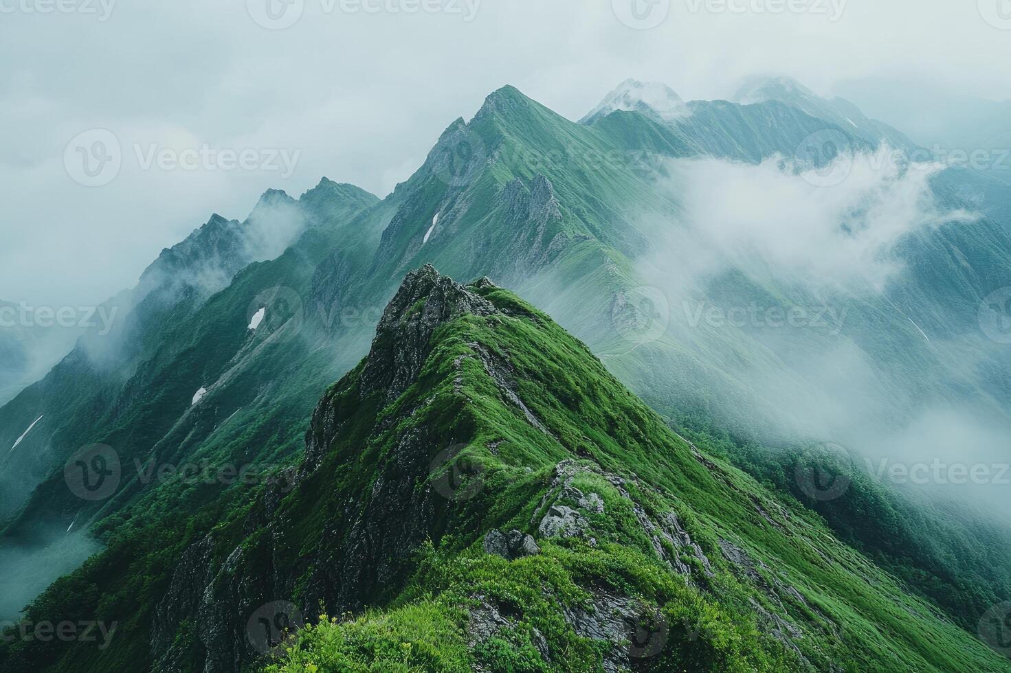 Green mountain peaks emerging from misty clouds in a serene landscape photo