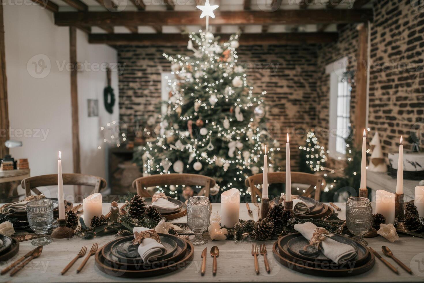 Christmas table setting decorated with candles, pine cones, and greenery in front of christmas tree photo