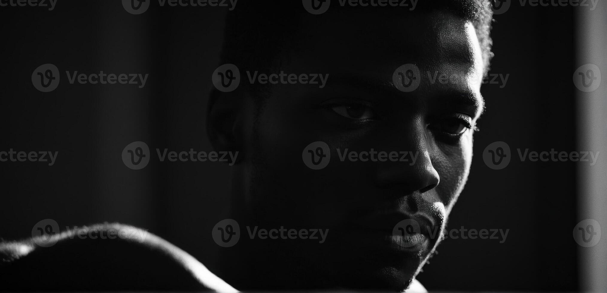 A black man is looking at the camera in a dark room photo