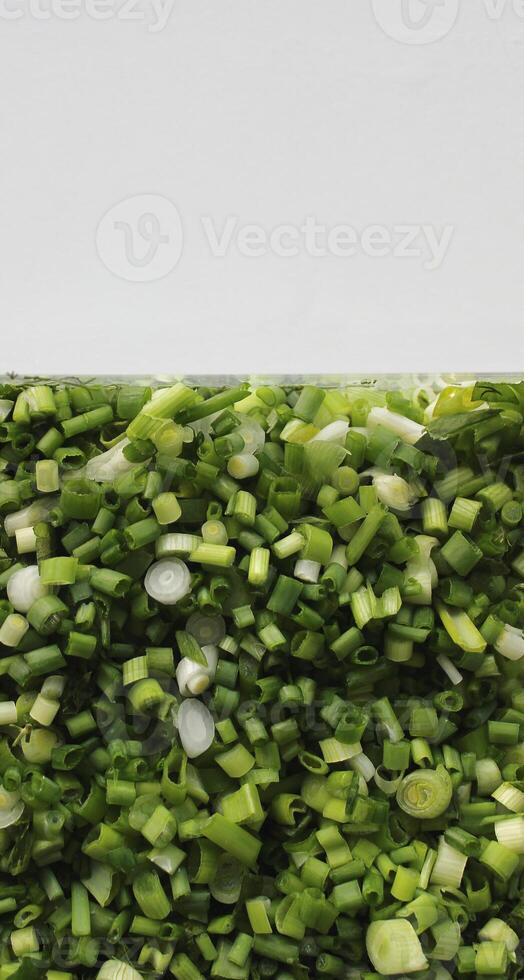 Front side of transparent container half filled with finely chopped onions and greens photo