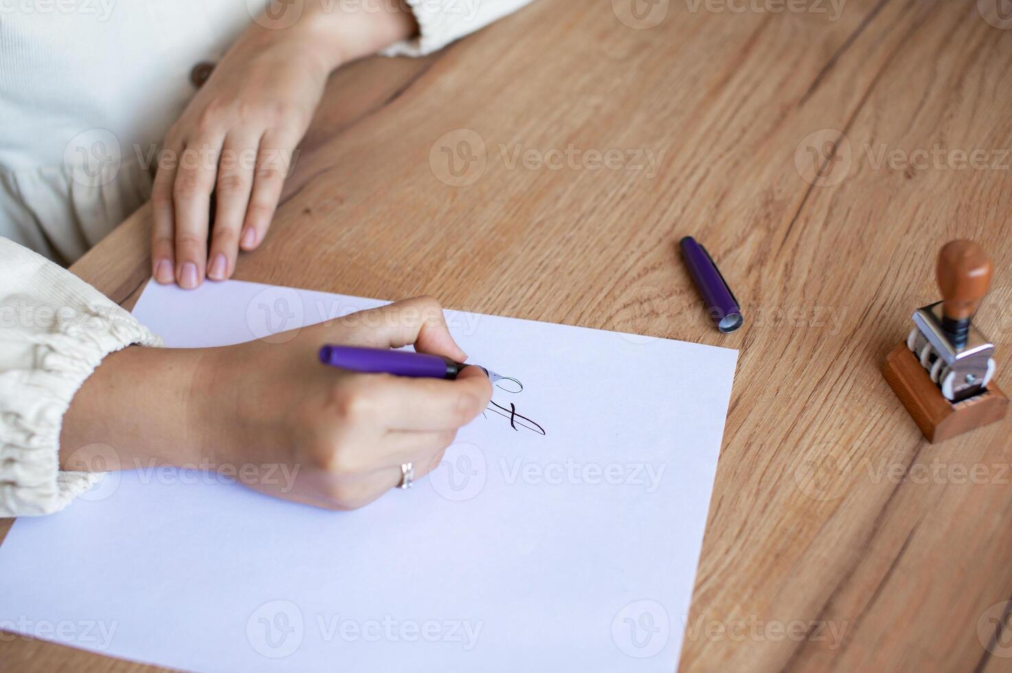 Person Writing Letter at Wooden Desk with Pen and Stamp photo