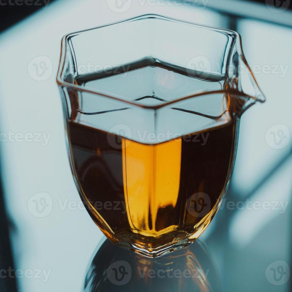 A stylish glass pitcher filled with vibrant amber liquid that stands out beautifully photo