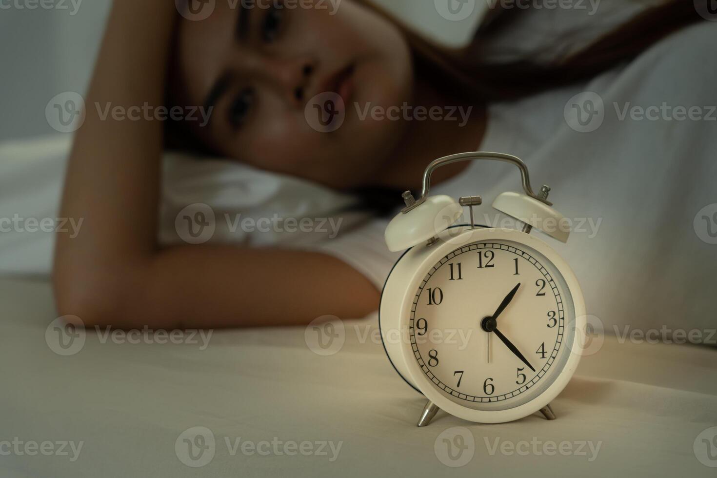 asian woman in bed late trying to sleep suffering insomnia, sleepless or scared in a nightmare, looking sad worried and stressed. Tired and headache or migraine waking up in the middle of the night. photo