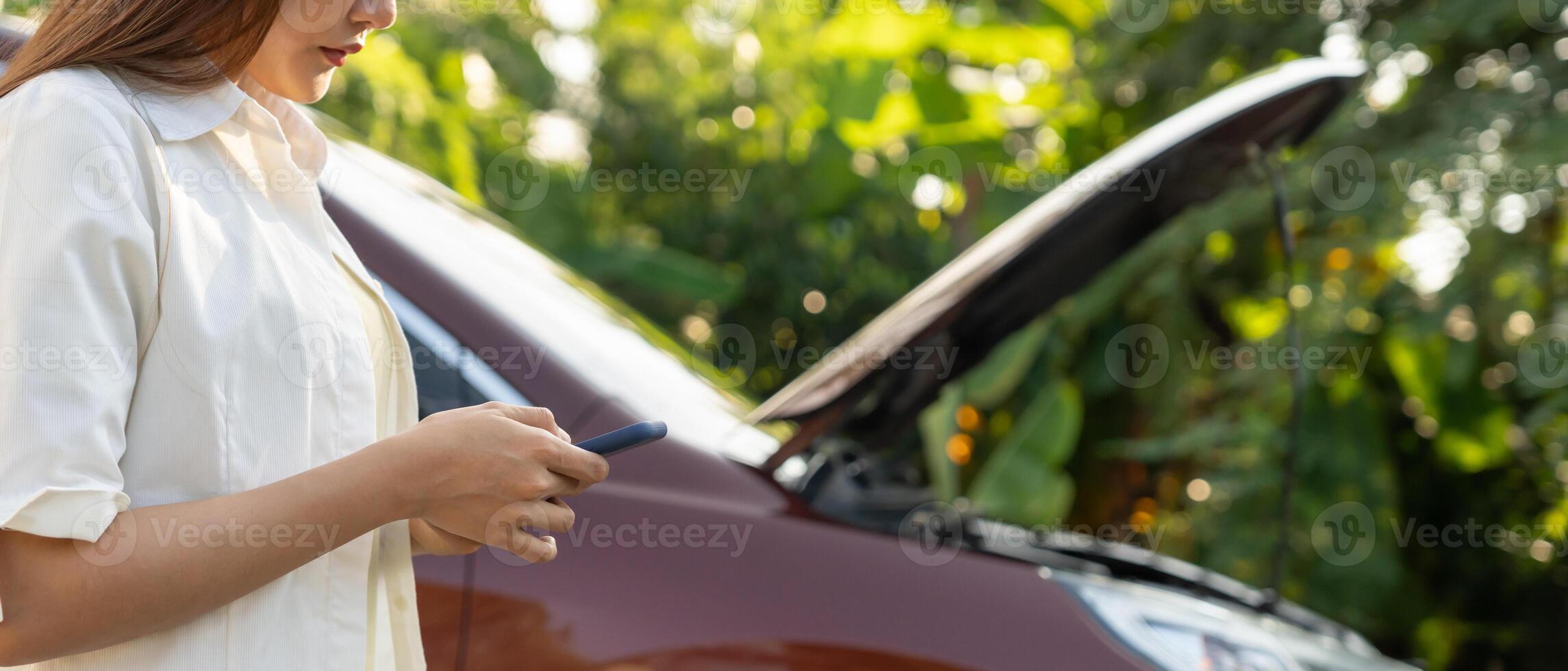 breakdown, broken car, repair. Woman uses mobile phone check insurance premiums through application due to car accident . Find garage to get car fixed during country tour, waiting for help, emergency. photo