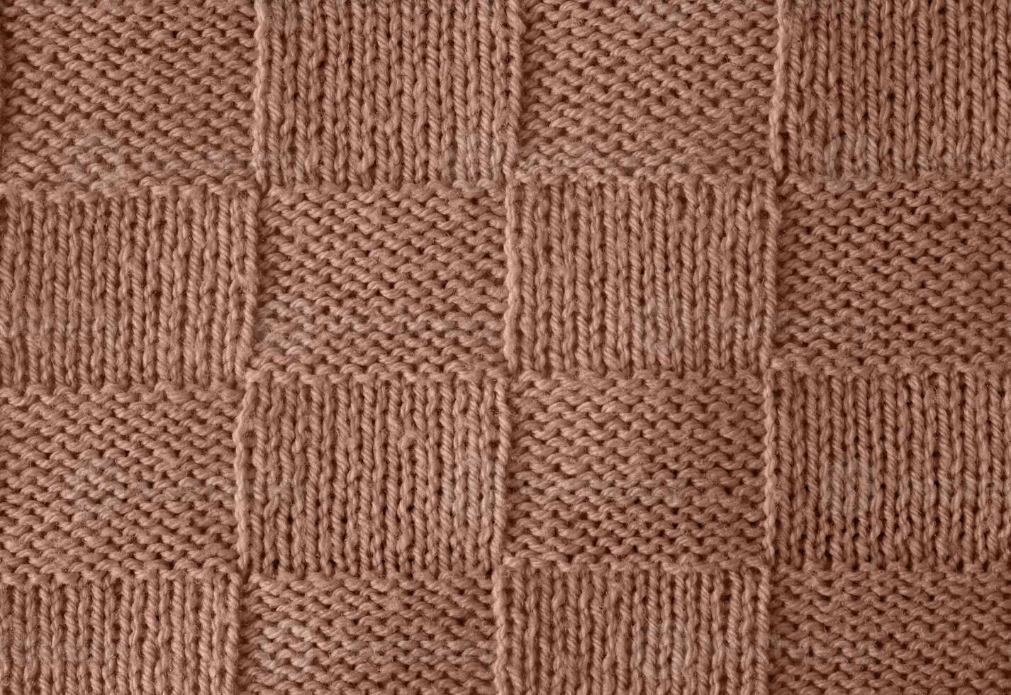 Texture of smooth knitted sweater with pattern. Handmade knitting wool or cotton fabric texture. Background of Large knit pattern with knitting needles or crochet. Mocha Mousse colour of 2025 year photo