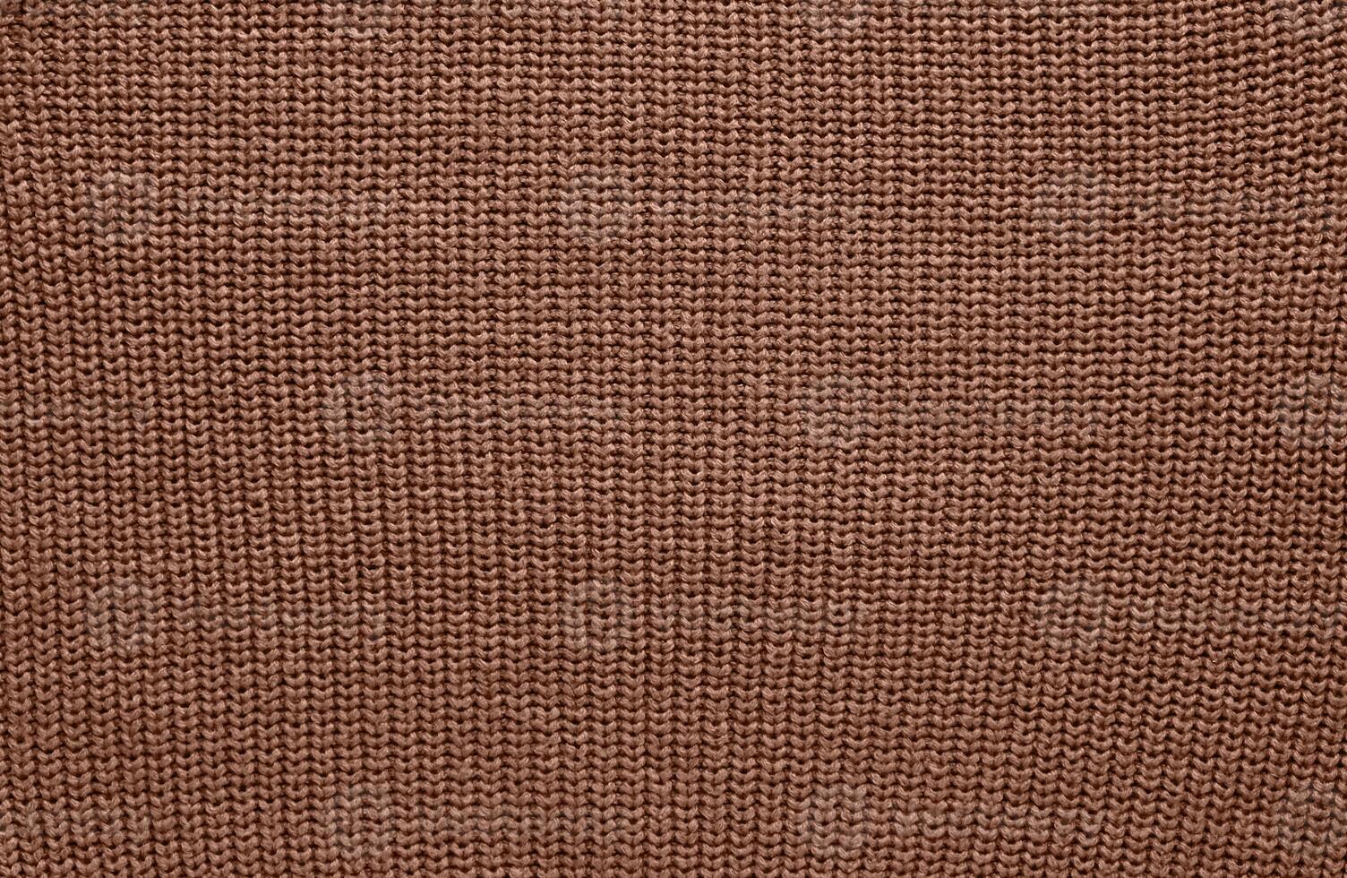 Texture of smooth knitted sweater with pattern. Handmade knitting wool or cotton fabric texture. Background of Large knit pattern with knitting needles or crochet. Mocha Mousse colour of 2025 year photo