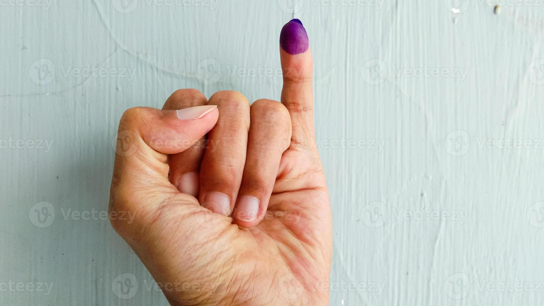 Hand with purple ink on the little finger, as a sign of having voted in the general election in Indonesia with isolated white background photo