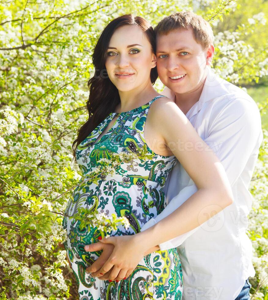 Young happy pregnant couple in the flowering spring park photo