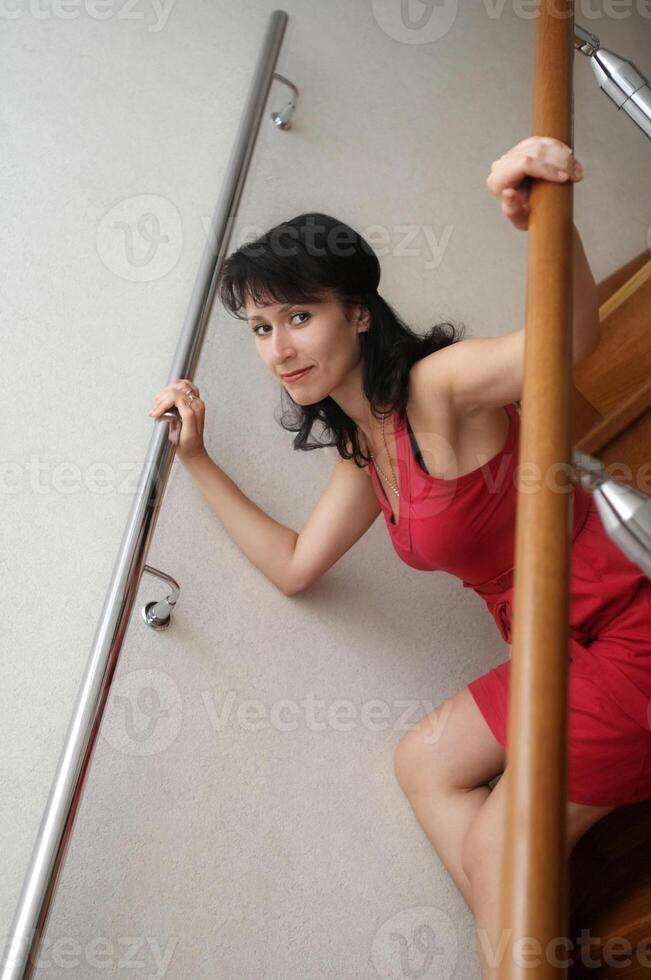 a woman in a red dress is sitting on the stairs photo