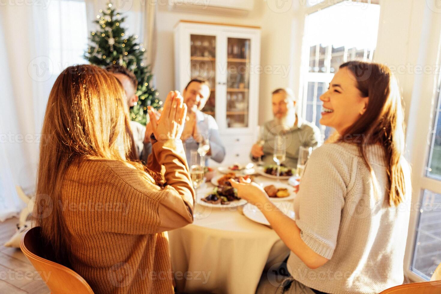 A happy big family at the dining table in the dining room at home. Relatives laugh and chat over a festive lunch. Men and women eat and have fun together. photo