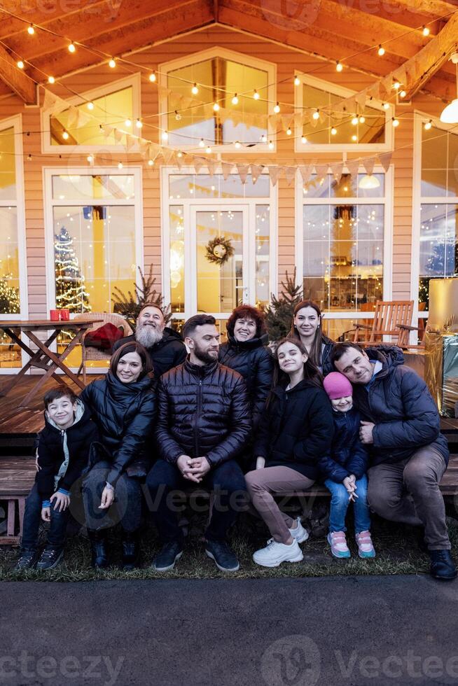 Big happy family in backyard of house. Several generations together on Christmas Eve. Grandparents, parents, children and grandchildren have fun together outdoors. photo