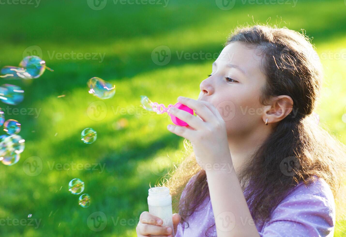 Little cute girl blowing soap bubbles outdoors photo