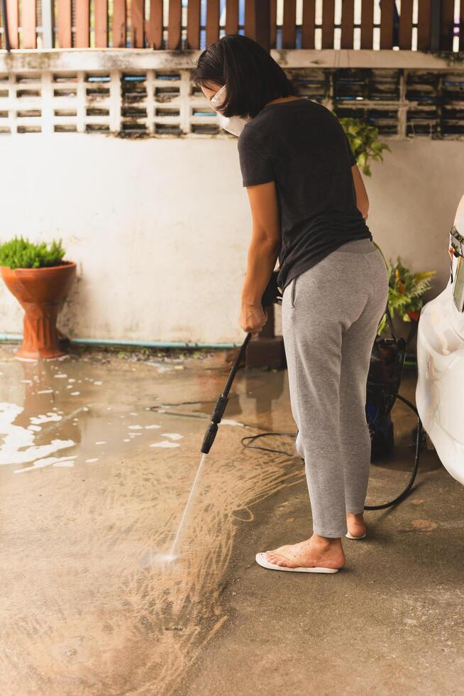 Woman cleaning concret floor with high pressure jet. photo