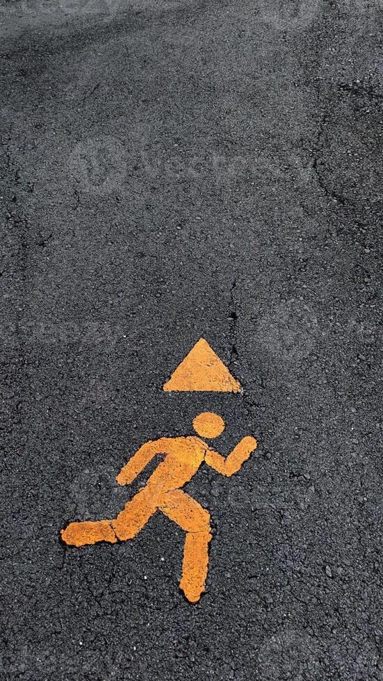 Safety sign indicating a running figure with a warning triangle. photo
