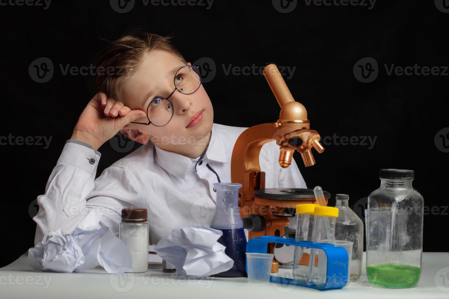A boy scientist researcher with a microscope is thinking about ideas in the laboratory. Surprise in the laboratory. Science and education. photo