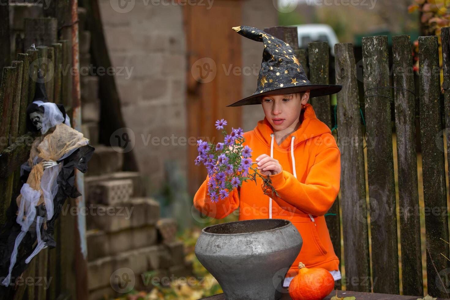 Halloween child with a sorcerer's hat on the background of an old creepy house.A wizard boy at a Halloween party. photo