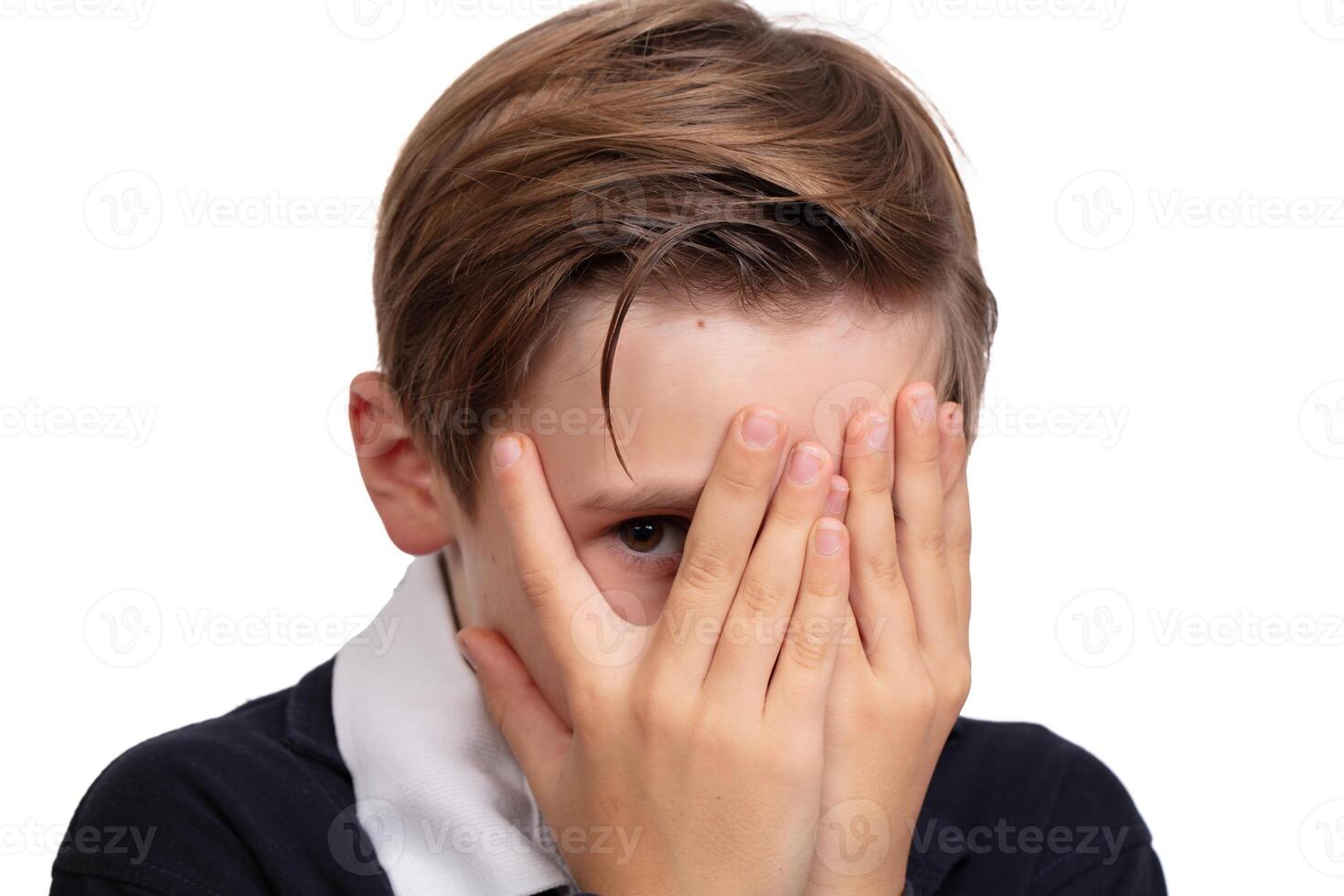 Portrait of a boy who is peeping, covered his face with his hands on a white background close-up. photo