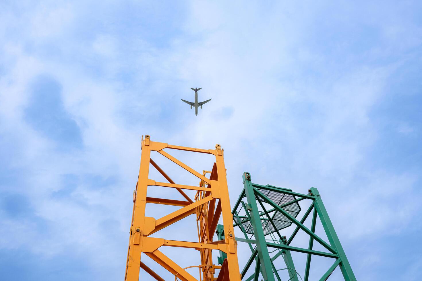 Tower crane in at construction site with air plane on sky in the background photo