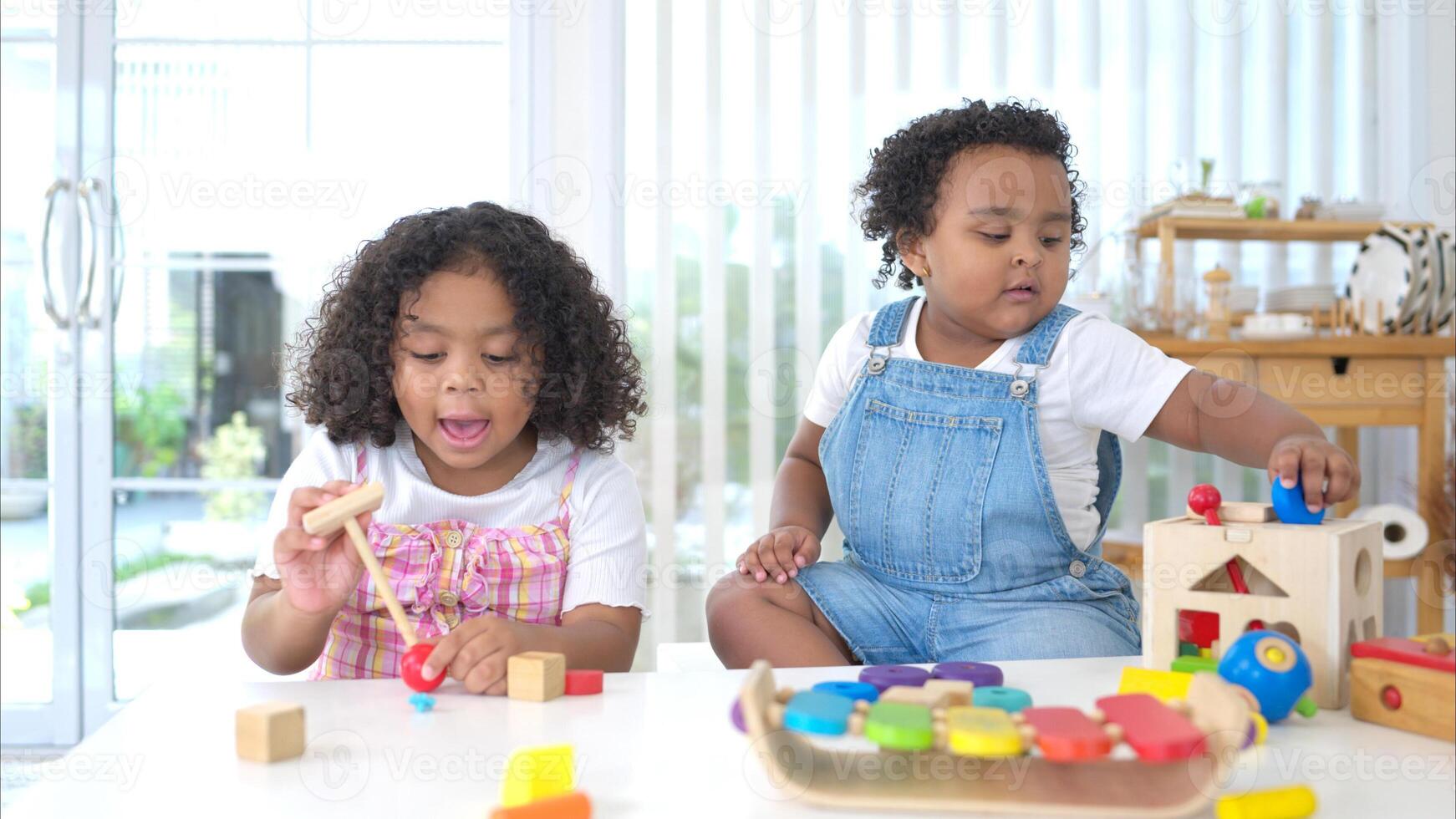 The older sister and younger sister sit on the floor and play the toy together photo