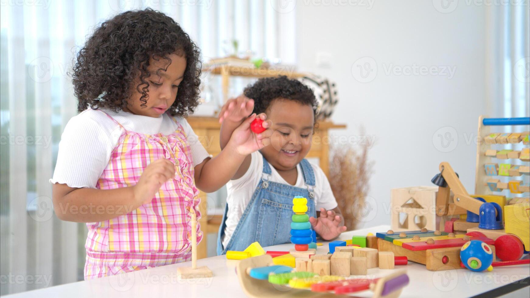 The older sister and younger sister sit on the floor and play the toy together photo