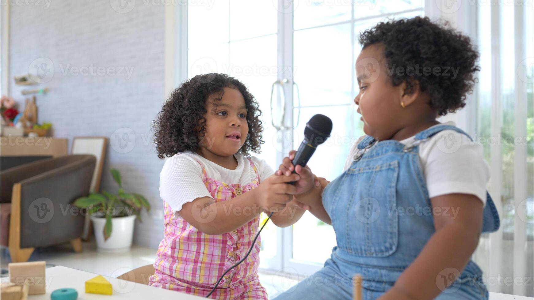 The older sister and younger sister clutching a microphone and sings cheerfully in the living room photo