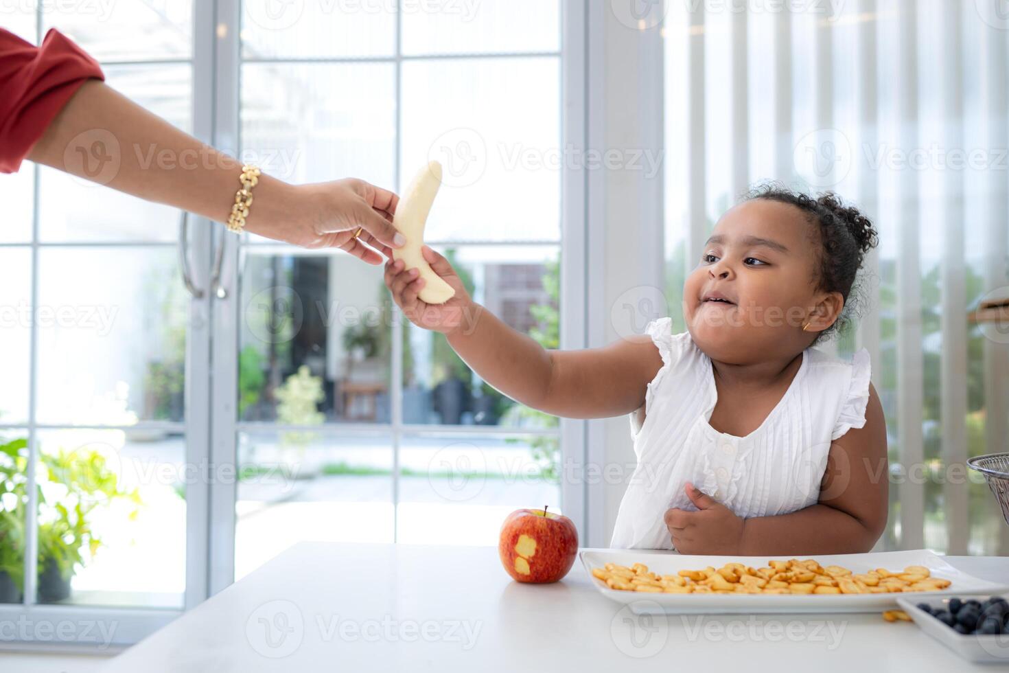 Mother peels bananas for her daughter to consume as a snack photo