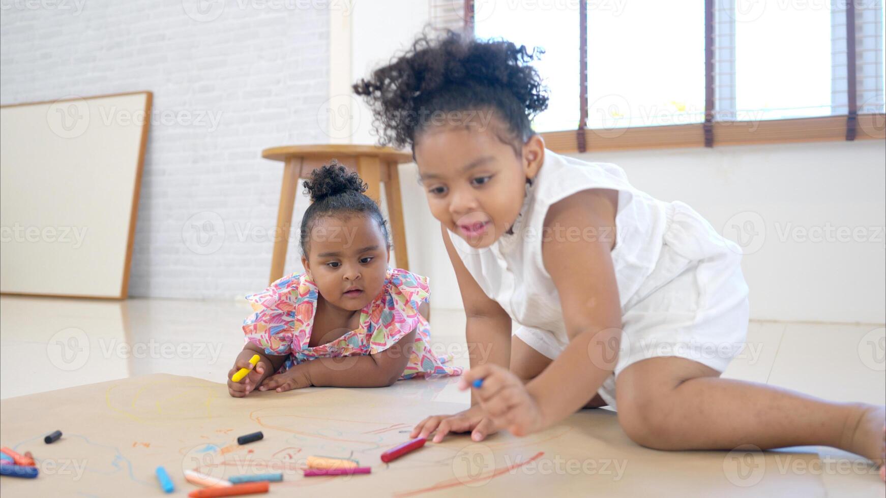 The older sister and younger sister sit on the floor and drawing together in the living room photo