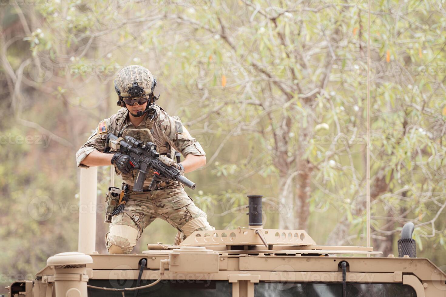 Soldiers in camouflage uniforms hold weapons ready to fire on the roof of a military communication vehicle photo