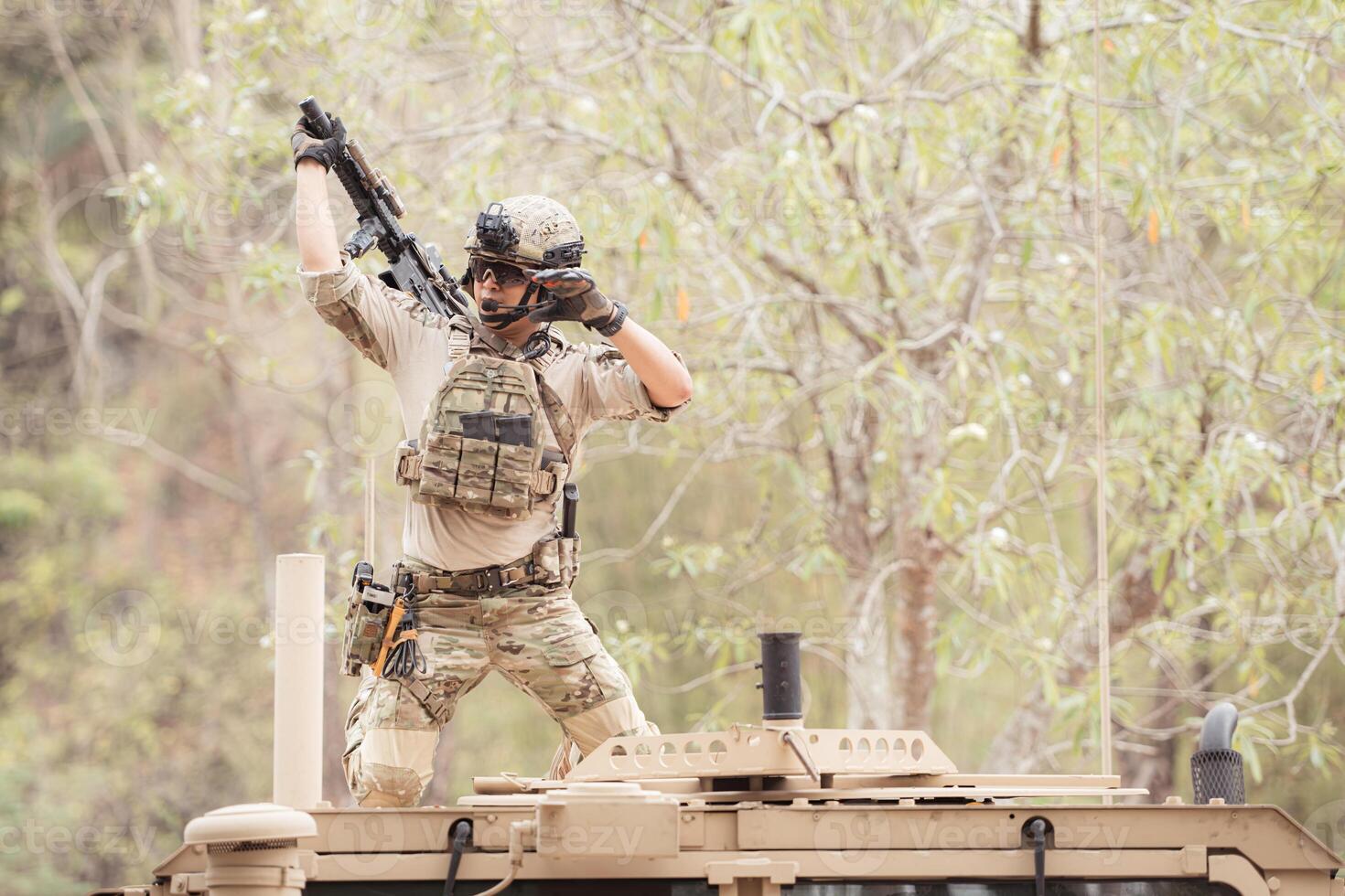 Soldiers in camouflage uniforms hold weapons ready to fire on the roof of a military communication vehicle photo
