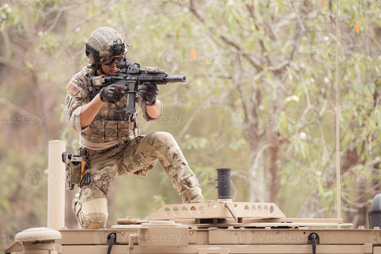 Soldiers in camouflage uniforms hold weapons ready to fire on the roof of a military communication vehicle photo