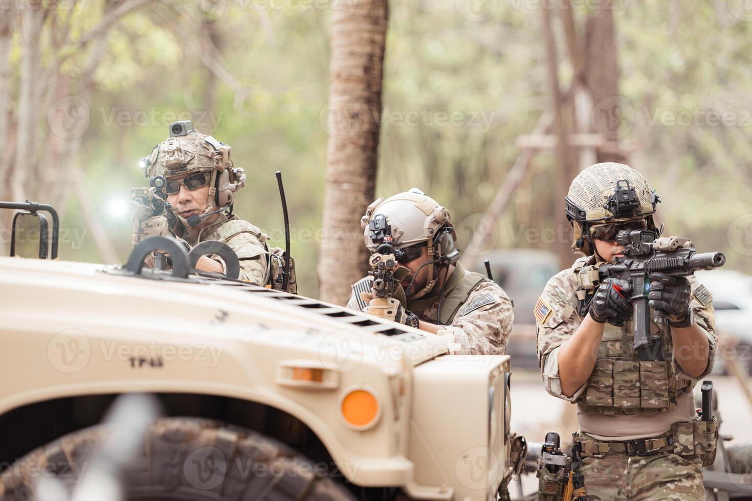 Soldiers in camouflage uniforms hold weapons ready to fire, By hiding on the side military communication vehicle photo