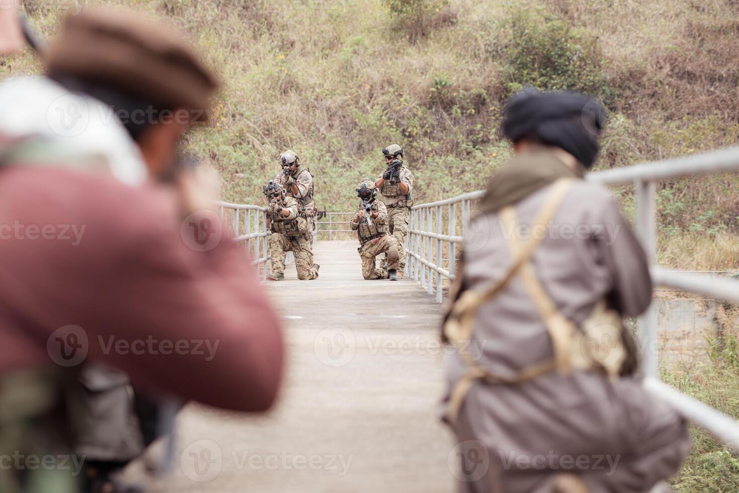 A group of Allied soldiers in camouflage wearing weapons clash with group of taliban soldiers photo