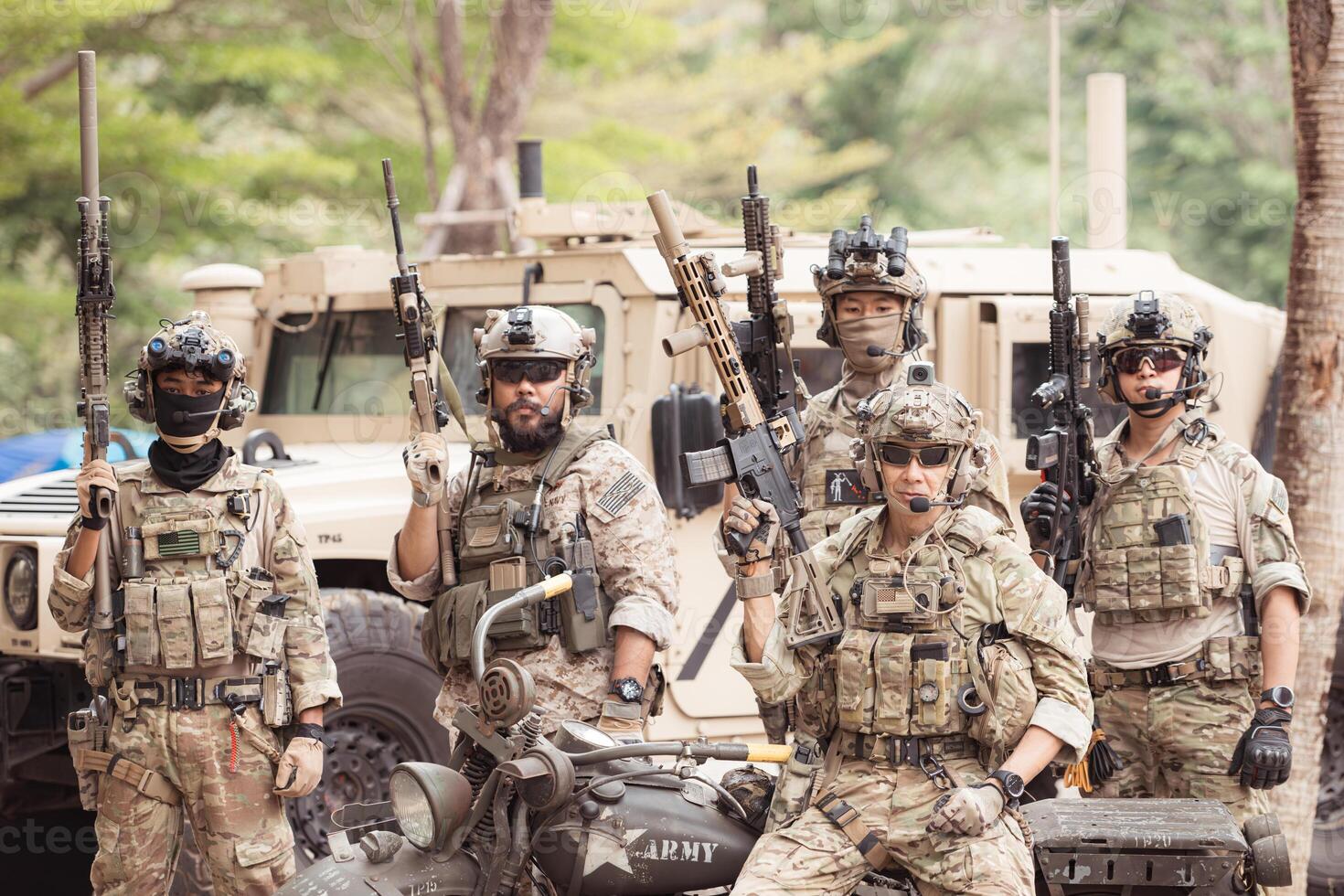 Portrait of soldiers in camouflage uniforms hold weapons in front of a military communication vehicle photo